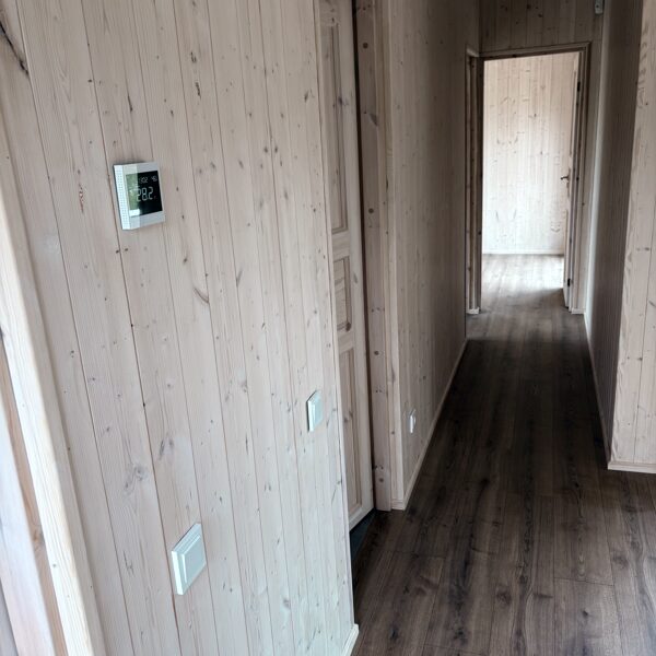 Vidaus vaizdas – klimato kontrolės valdiklis, medinės sienos ir laminuotos grindys